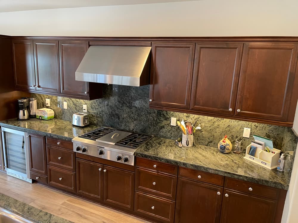 Modern kitchen with dark wood cabinets, green granite countertop, and high-end appliances.