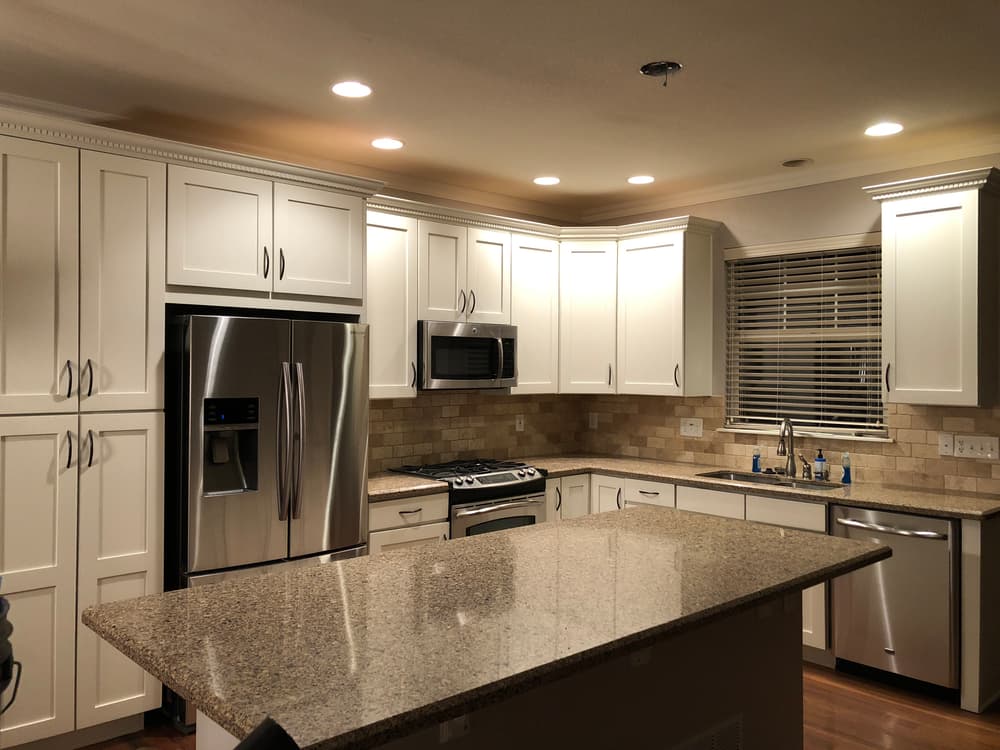 Modern kitchen with stainless steel appliances, white cabinets, and granite countertop.