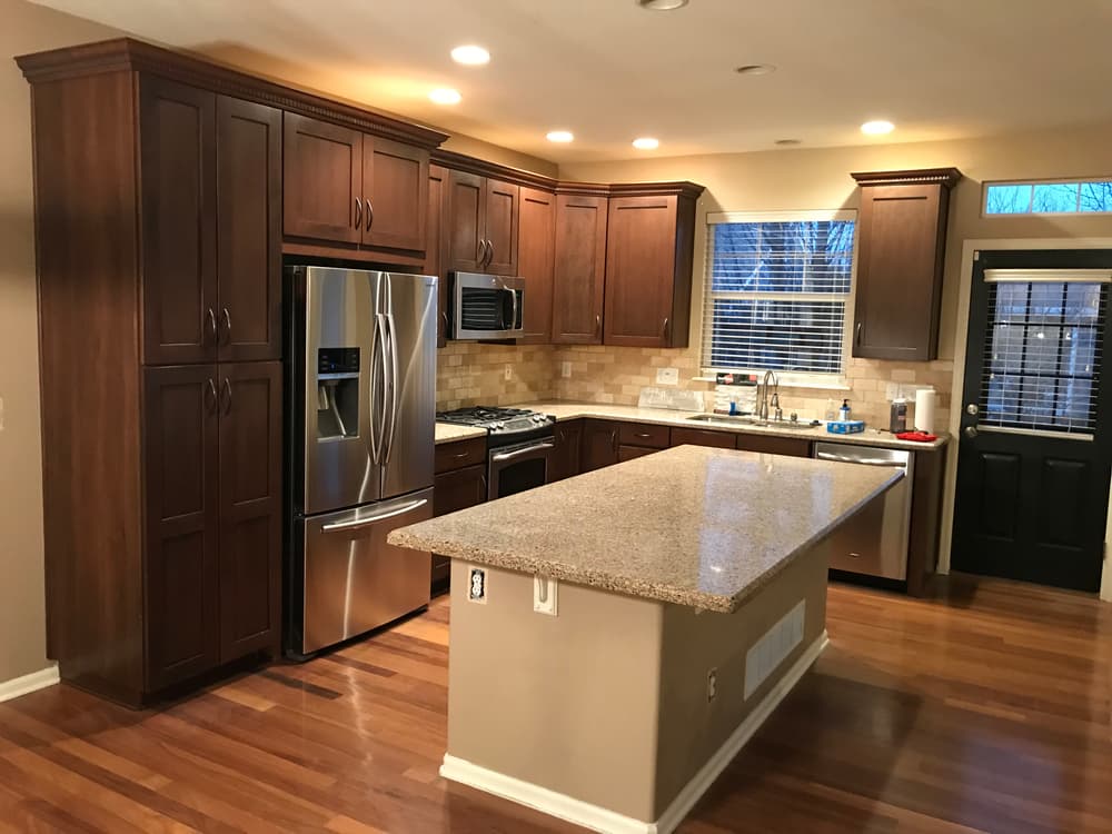 Modern kitchen with dark wood cabinets, stainless steel appliances, and granite island.
